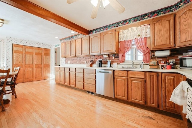 kitchen featuring light wood finished floors, dishwasher, beamed ceiling, light countertops, and a sink