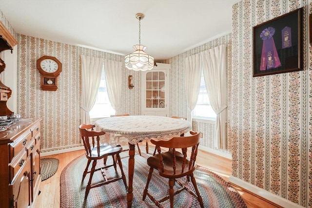 dining room featuring a healthy amount of sunlight, wallpapered walls, and light wood-style floors