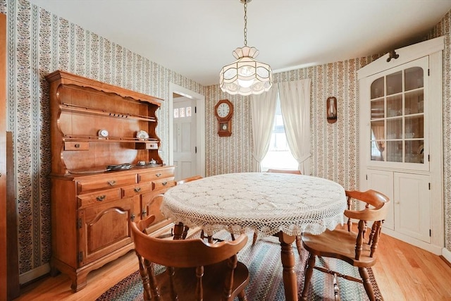 dining area with light wood-style floors, baseboards, and wallpapered walls