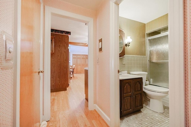 bathroom featuring tile walls, toilet, vanity, wood finished floors, and wallpapered walls