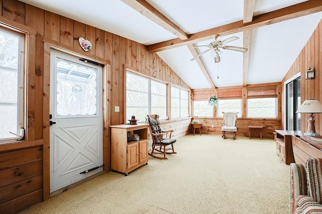 interior space featuring light carpet, vaulted ceiling with beams, wooden walls, and ceiling fan