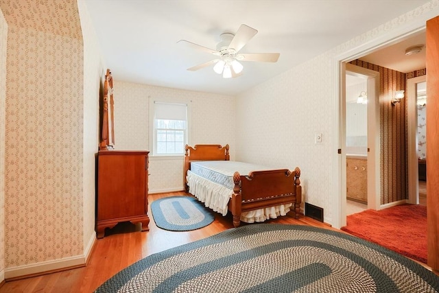 bedroom featuring ceiling fan, light wood-style flooring, baseboards, and wallpapered walls