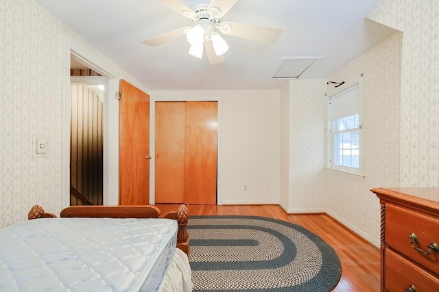 bedroom with wallpapered walls, attic access, baseboards, and light wood finished floors