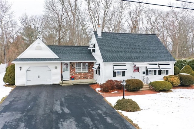 view of front of house with aphalt driveway, brick siding, a chimney, a shingled roof, and a garage