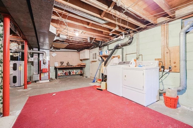 unfinished below grade area featuring heating unit, washing machine and clothes dryer, and hybrid water heater