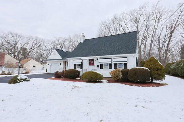 cape cod house featuring a garage and a chimney