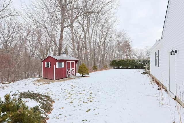 yard covered in snow featuring a storage shed and an outbuilding