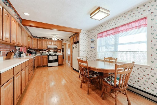 kitchen with under cabinet range hood, light wood-style floors, light countertops, appliances with stainless steel finishes, and wallpapered walls