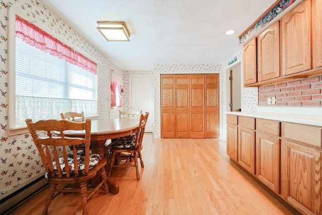 dining space featuring light wood finished floors and wallpapered walls