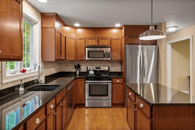 71 Fox Run Dr, Ayer, MA 01432 - kitchen featuring appliances with stainless steel finishes, a sink, light wood-type flooring, brown cabinetry, and backsplash