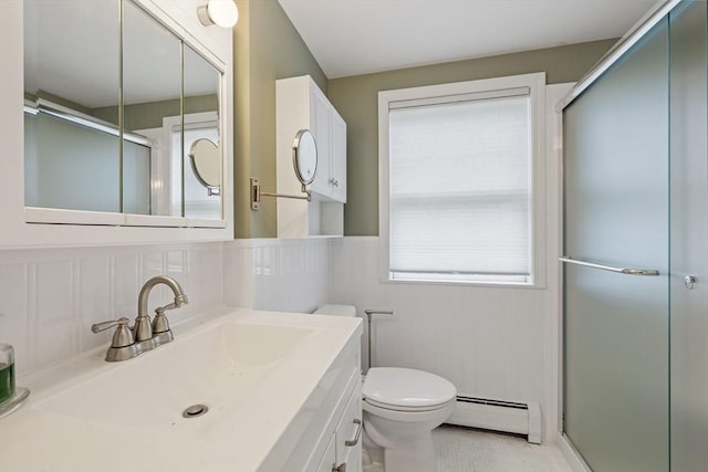 full bathroom with a baseboard heating unit, a shower stall, toilet, vanity, and a wainscoted wall