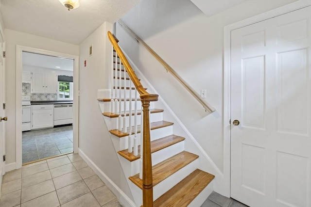 staircase featuring tile patterned flooring and baseboards