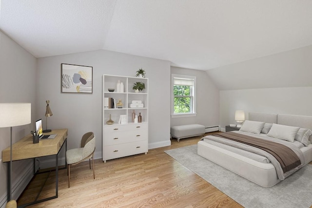 bedroom featuring lofted ceiling, baseboard heating, light wood finished floors, an office area, and baseboards