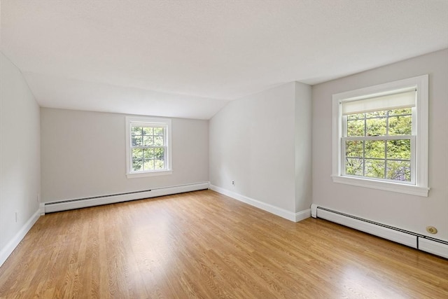unfurnished room featuring a baseboard radiator, wood finished floors, baseboards, and vaulted ceiling