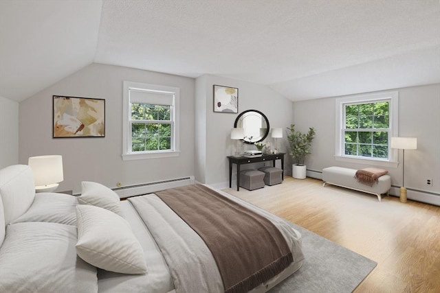 bedroom with a baseboard heating unit, vaulted ceiling, wood finished floors, and multiple windows