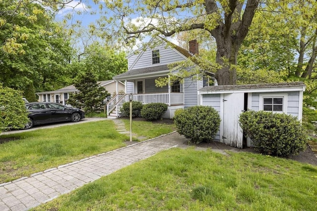 view of front of home featuring a chimney, a porch, and a front lawn