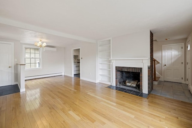 unfurnished living room featuring a baseboard radiator, a chandelier, a brick fireplace, hardwood / wood-style floors, and built in shelves