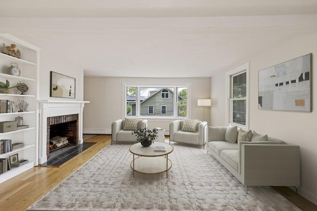 living area featuring baseboard heating, wood finished floors, and a brick fireplace