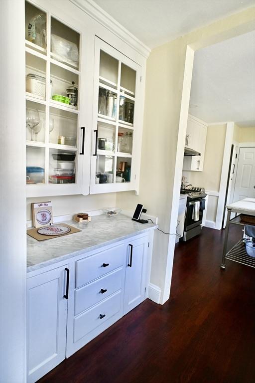 bar area featuring range with gas stovetop, dark wood finished floors, under cabinet range hood, and baseboards