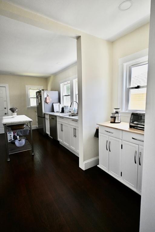 kitchen with baseboards, dishwasher, freestanding refrigerator, and light countertops