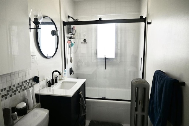 full bath featuring radiator heating unit, shower / bath combination with glass door, toilet, vanity, and tile walls