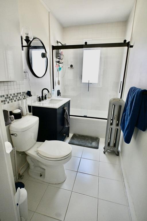 bathroom featuring tile patterned floors, toilet, radiator, vanity, and backsplash