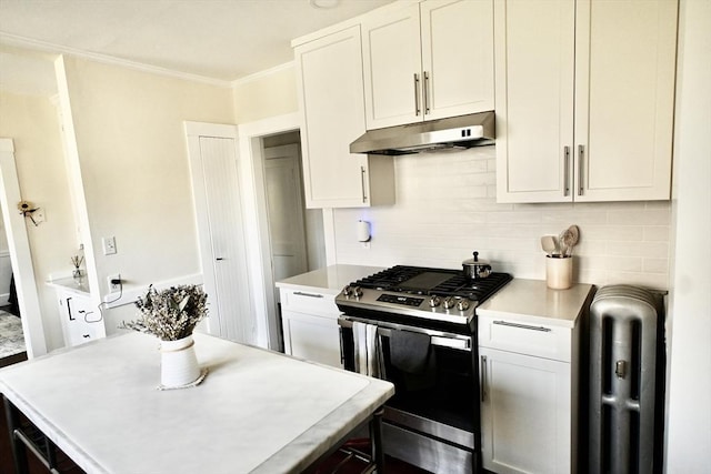 kitchen featuring stainless steel gas stove, under cabinet range hood, radiator, light countertops, and decorative backsplash