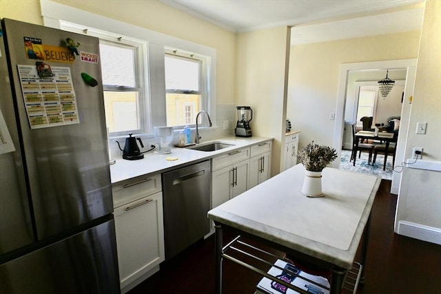 kitchen featuring appliances with stainless steel finishes, a sink, light countertops, dark wood-type flooring, and crown molding