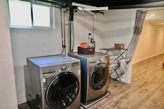 clothes washing area with washing machine and clothes dryer, light wood finished floors, and baseboards