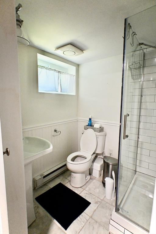 bathroom featuring a baseboard radiator, toilet, and a shower stall