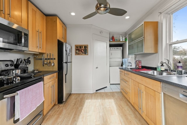 kitchen with sink, crown molding, light hardwood / wood-style flooring, appliances with stainless steel finishes, and stacked washer / drying machine