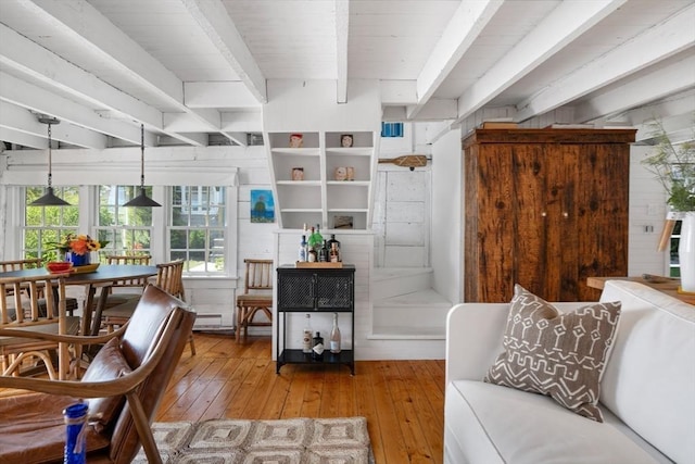 living area with beamed ceiling and light wood-type flooring