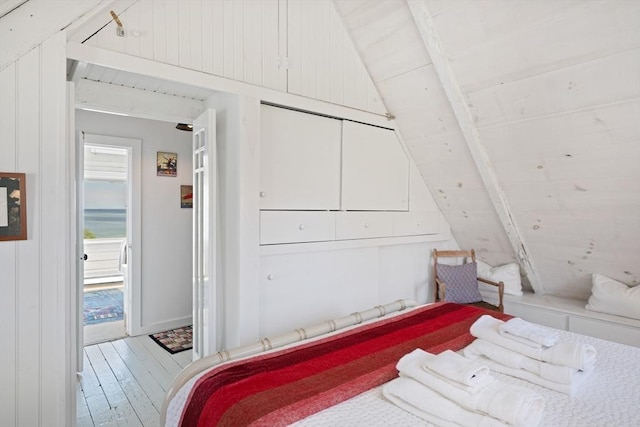 bedroom with access to exterior, hardwood / wood-style flooring, and vaulted ceiling