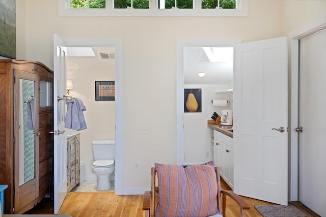 bathroom with vanity, hardwood / wood-style floors, a skylight, and toilet