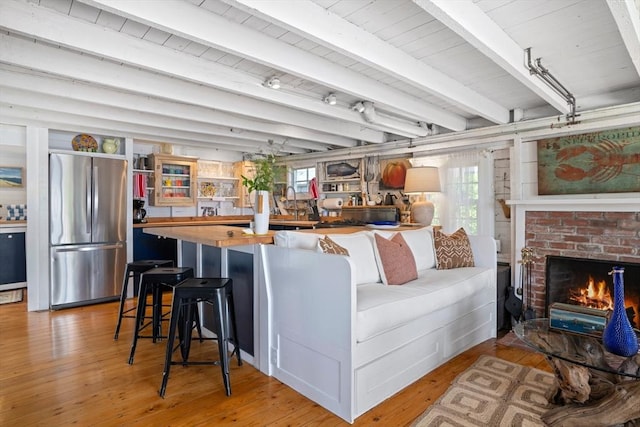 interior space featuring beamed ceiling, a brick fireplace, and hardwood / wood-style floors