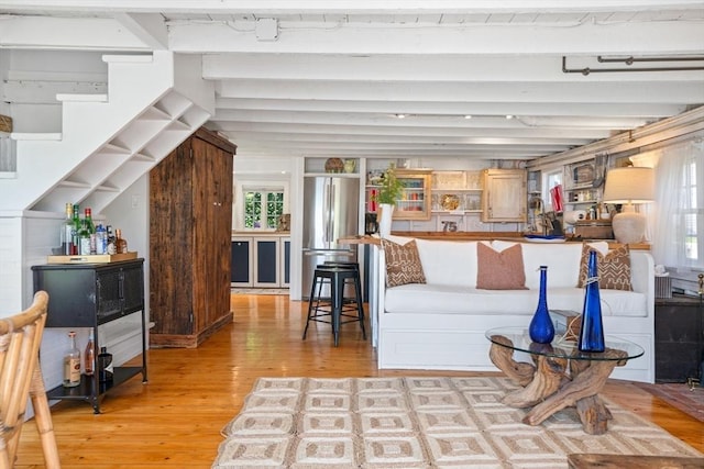 living room featuring lofted ceiling with beams and light hardwood / wood-style flooring