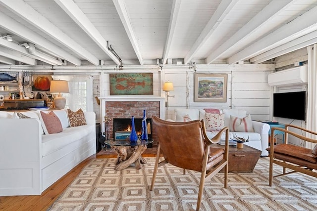 living room with beamed ceiling, a fireplace, and light wood-type flooring