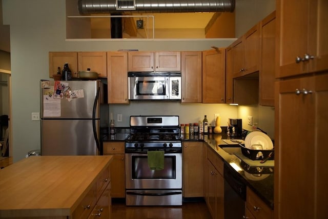 kitchen featuring brown cabinetry, appliances with stainless steel finishes, and butcher block counters