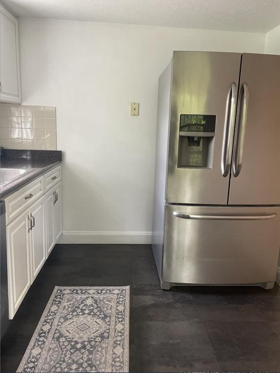 8 Zabriskie Unit 8B, Newburyport, MA 01950 - kitchen featuring stainless steel fridge with ice dispenser, white cabinets, tasteful backsplash, and baseboards