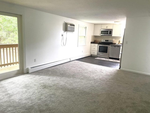 8 Zabriskie Unit 8B, Newburyport, MA 01950 - kitchen with appliances with stainless steel finishes, a baseboard heating unit, a wall mounted AC, white cabinets, and dark colored carpet