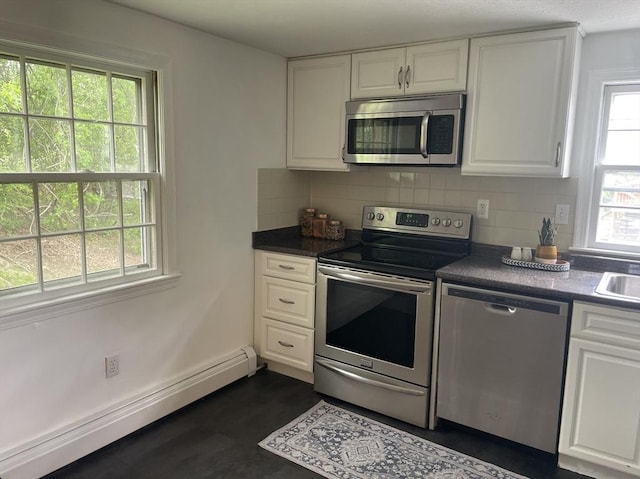 8 Zabriskie Unit 8B, Newburyport, MA 01950 - kitchen featuring appliances with stainless steel finishes, a baseboard heating unit, white cabinets, backsplash, and dark countertops