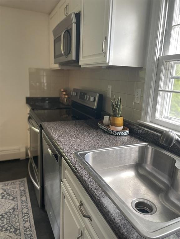 8 Zabriskie Unit 8B, Newburyport, MA 01950 - kitchen featuring appliances with stainless steel finishes, a sink, a baseboard radiator, white cabinetry, and dark countertops