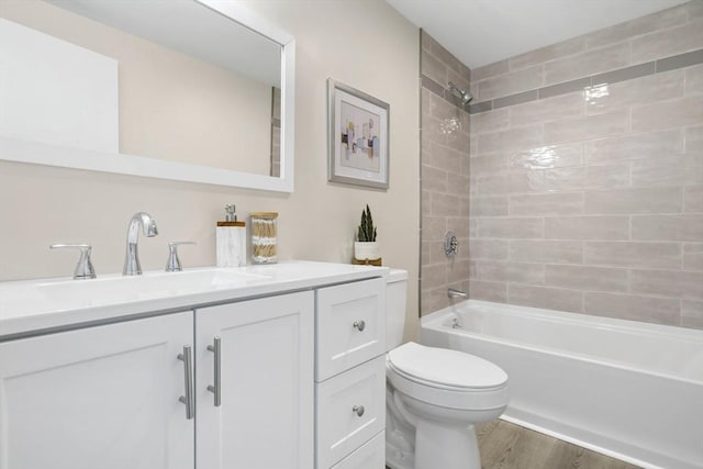 full bathroom featuring hardwood / wood-style flooring, toilet, vanity, and tiled shower / bath