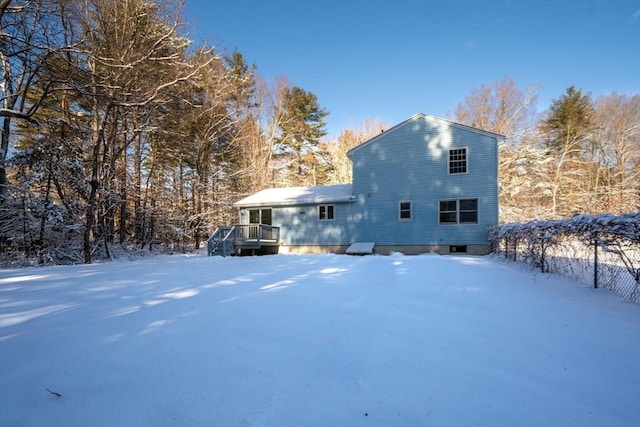 snow covered rear of property with a deck