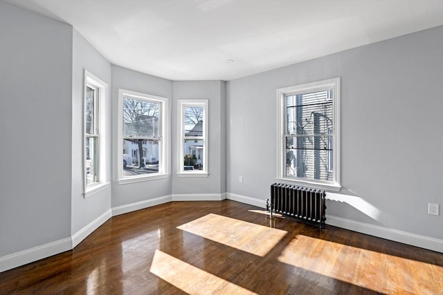 empty room featuring radiator and dark hardwood / wood-style floors