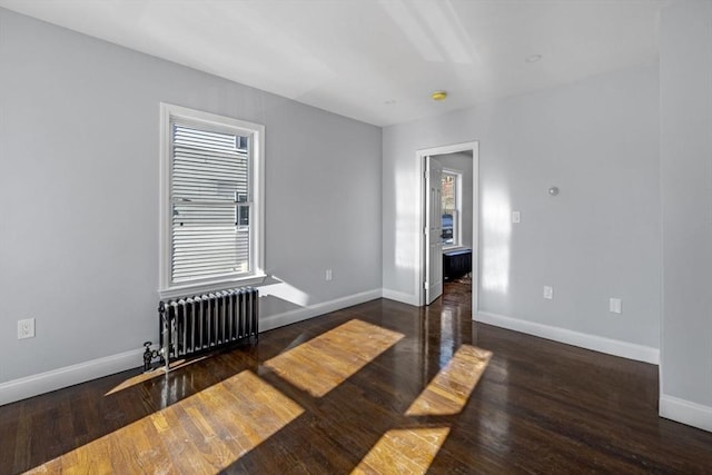 spare room with radiator heating unit and dark hardwood / wood-style floors