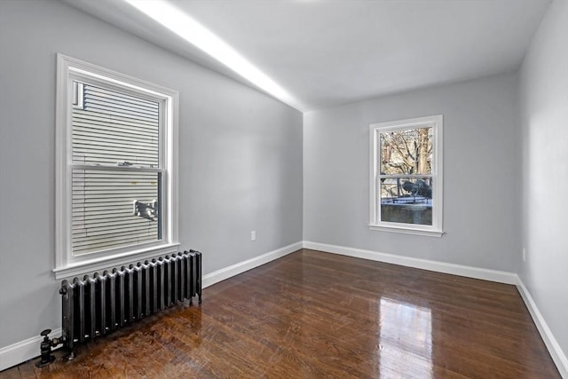 spare room featuring radiator and dark hardwood / wood-style flooring