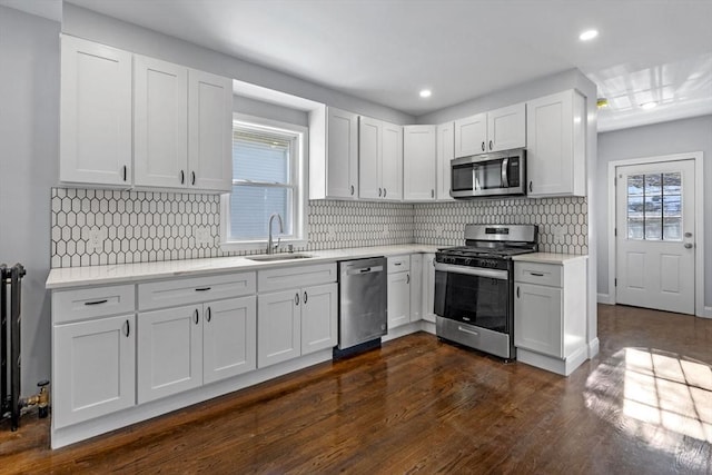 kitchen with white cabinets, stainless steel appliances, dark wood-type flooring, sink, and tasteful backsplash