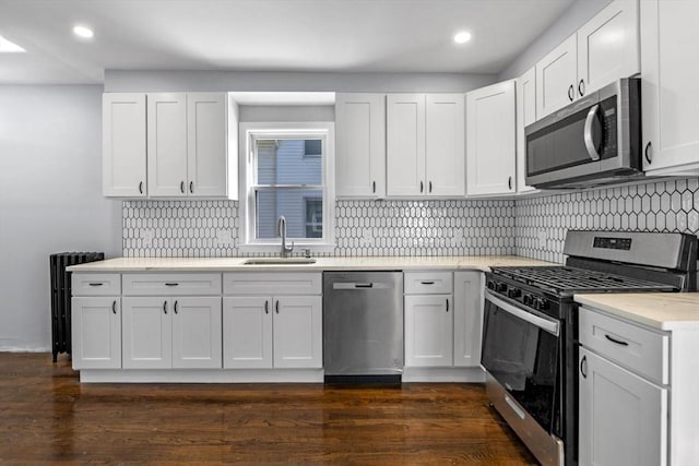 kitchen featuring appliances with stainless steel finishes, white cabinetry, dark hardwood / wood-style floors, and sink