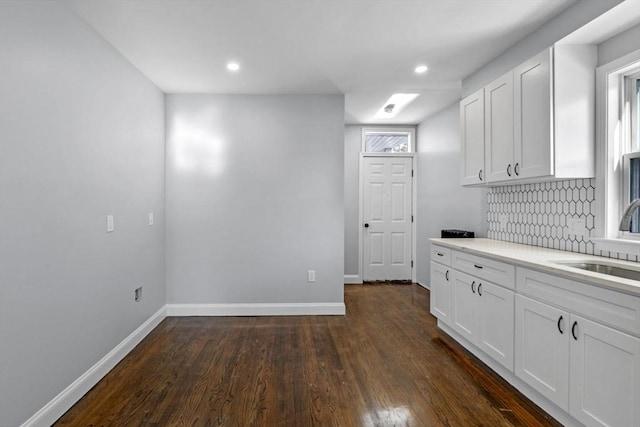 kitchen with white cabinets, dark wood-type flooring, tasteful backsplash, and sink